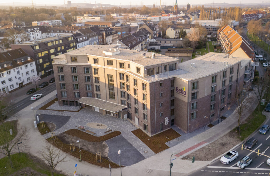 Fertiggestellter mehrgeschossiger Neubau mit Klinkerfassade und Außenanlagen im städtischen Umfeld