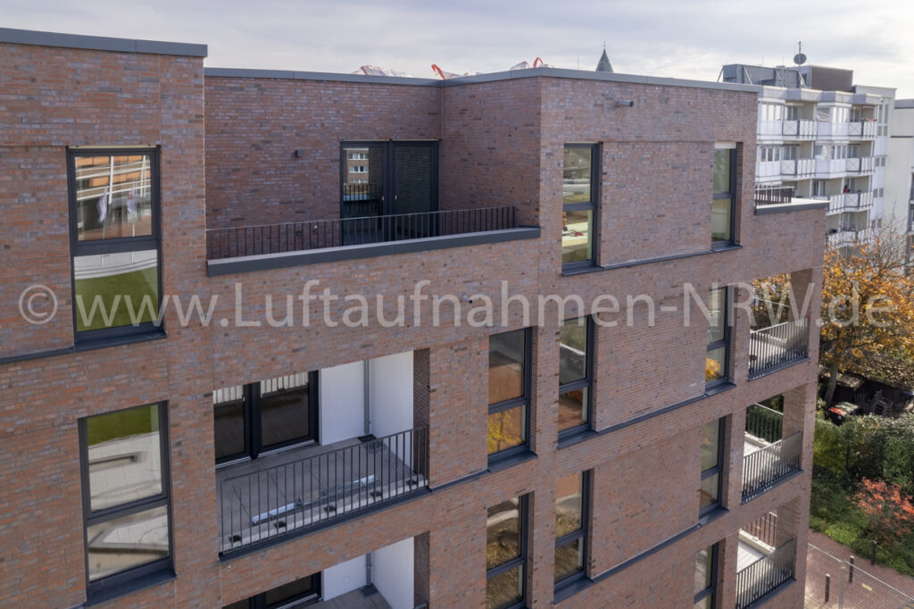 Nahaufnahme einer Klinkerfassade mit Balkonen und Fenstern aus erhöhter Perspektive