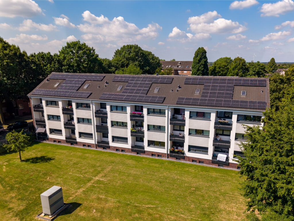 Luftaufnahme eines Mehrfamilienhauses in Nettetal mit Balkonen, Solarmodulen und Grünfläche